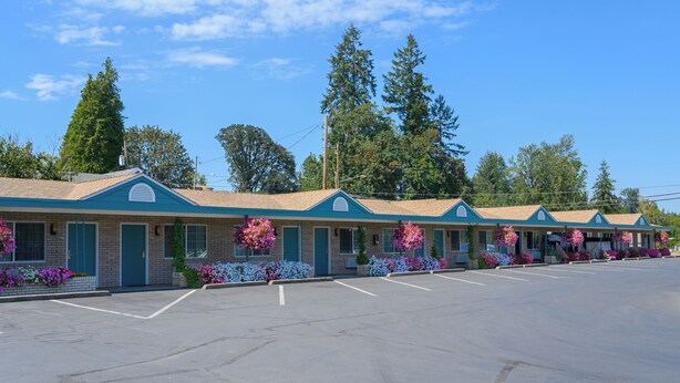 A row of motel buildings with a parking lot in front. - Sweet Home Inn (Sweet Home)