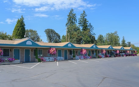 A row of motel buildings with a parking lot in front.