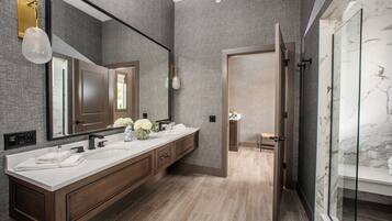 A modern bathroom with two sinks, a large mirror, and a glass shower enclosure.