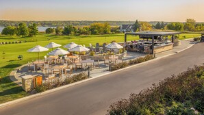 A golf course with outdoor seating and a covered area. - Destination Geneva National (Lake Geneva)