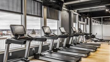 A row of treadmills in a gym with large windows and a view of a snowy landscape.