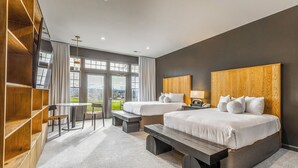 A modern hotel room with two beds, a dining area, and a view of the outdoors. - Destination Geneva National (Lake Geneva)