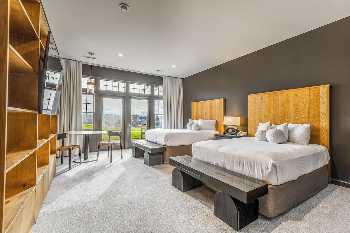 Ein modernes Hotelzimmer mit zwei Betten, einem Essbereich und Blick ins Freie.