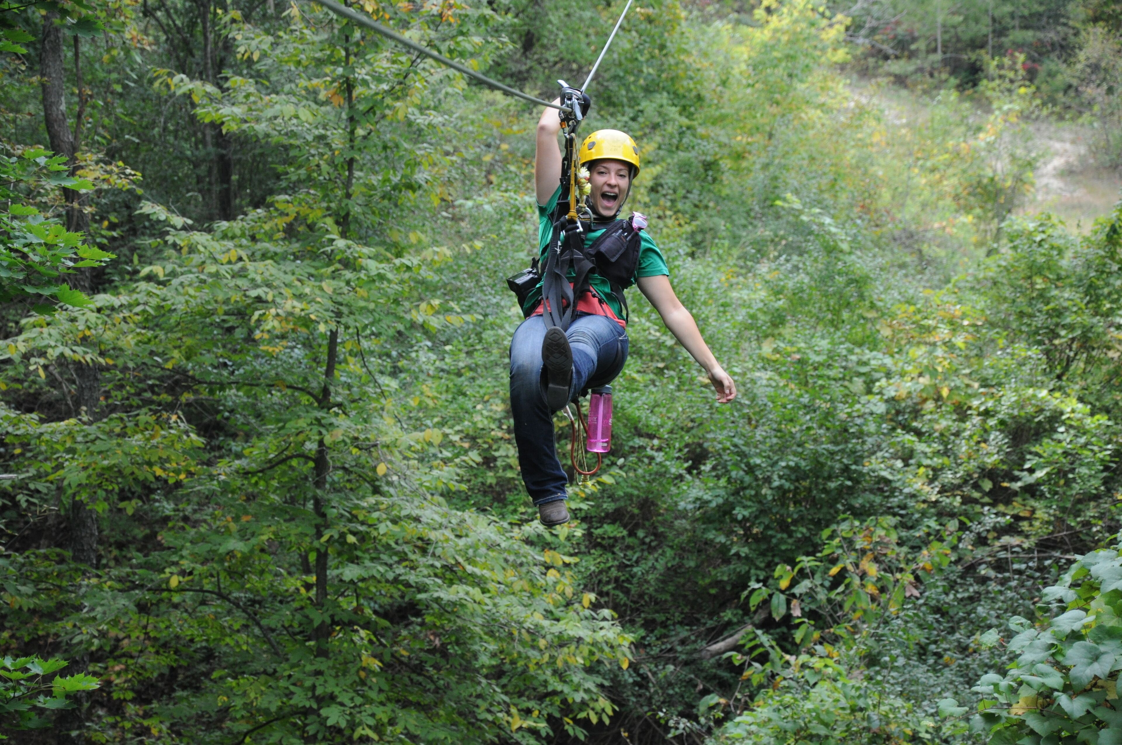 A person zip-lining through a forested area.