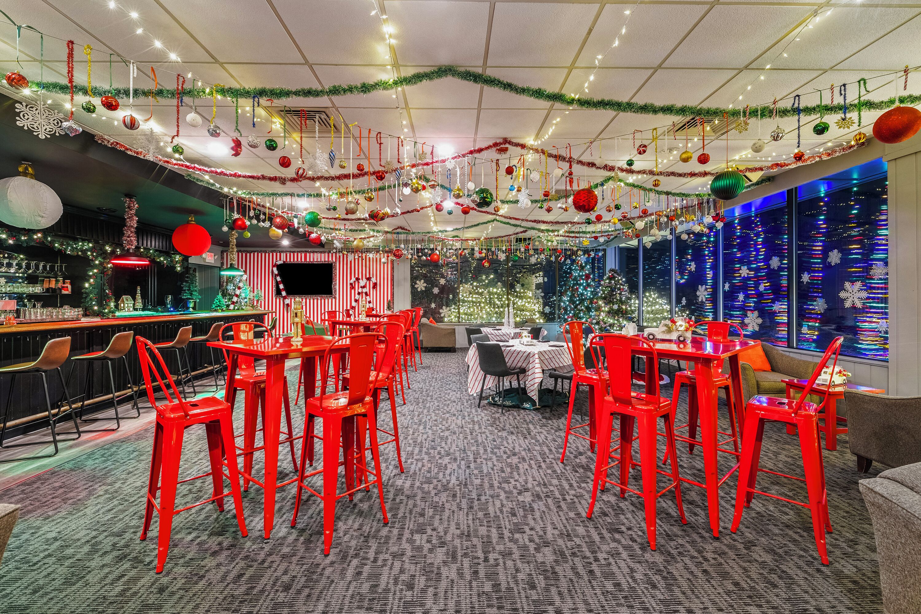 A restaurant with red chairs and tables, decorated with Christmas ornaments and lights.