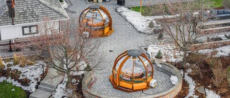 Een rond zitgedeelte buiten, met een centrale tafel en banken, omgeven door een bakstenen muur en een met sneeuw bedekte grond.
