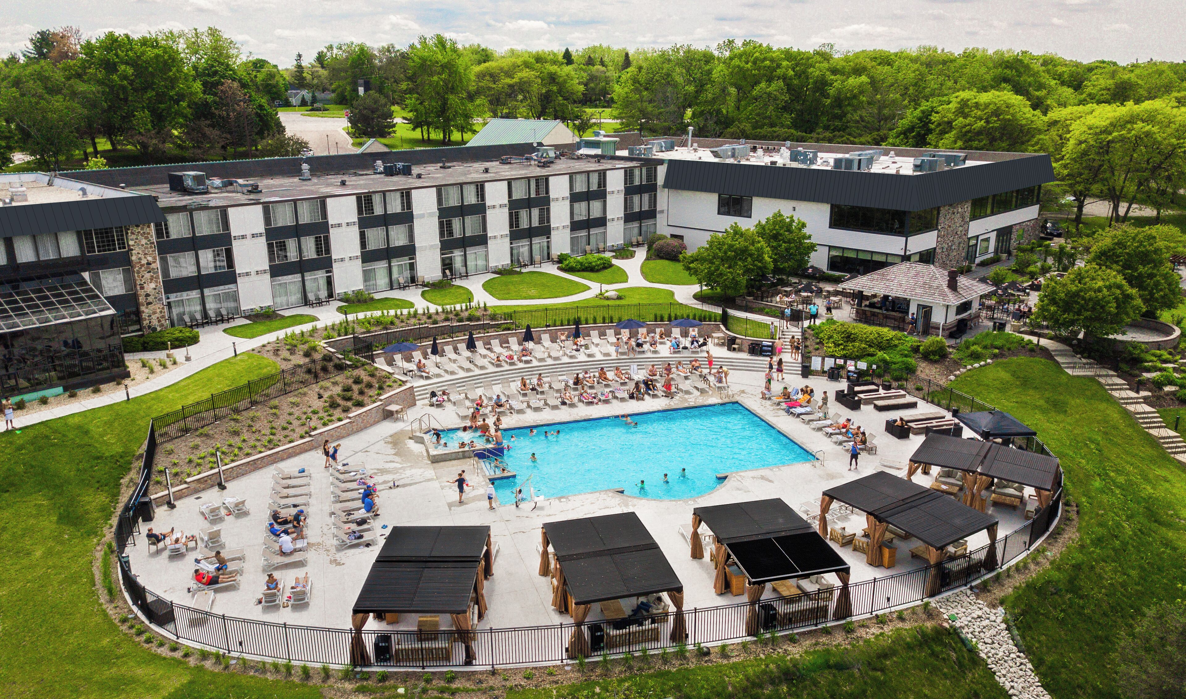 A hotel with a large swimming pool, outdoor seating areas, and a well-maintained garden.