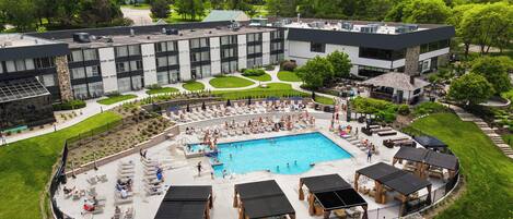 Ein Hotel mit großem Schwimmbad, Sitzgelegenheiten im Freien und einem gepflegten Garten.