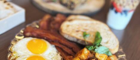 Un plato de desayuno con huevos, tocino y verduras salteadas.