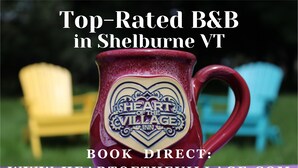 A red mug with "Heart of the Village Inn" logo, a yellow chair, and a blue chair in the background.