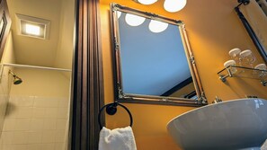A bathroom with a large mirror, a bathtub, a sink, and a towel rack. - Heart of the Village Inn (Shelburne)