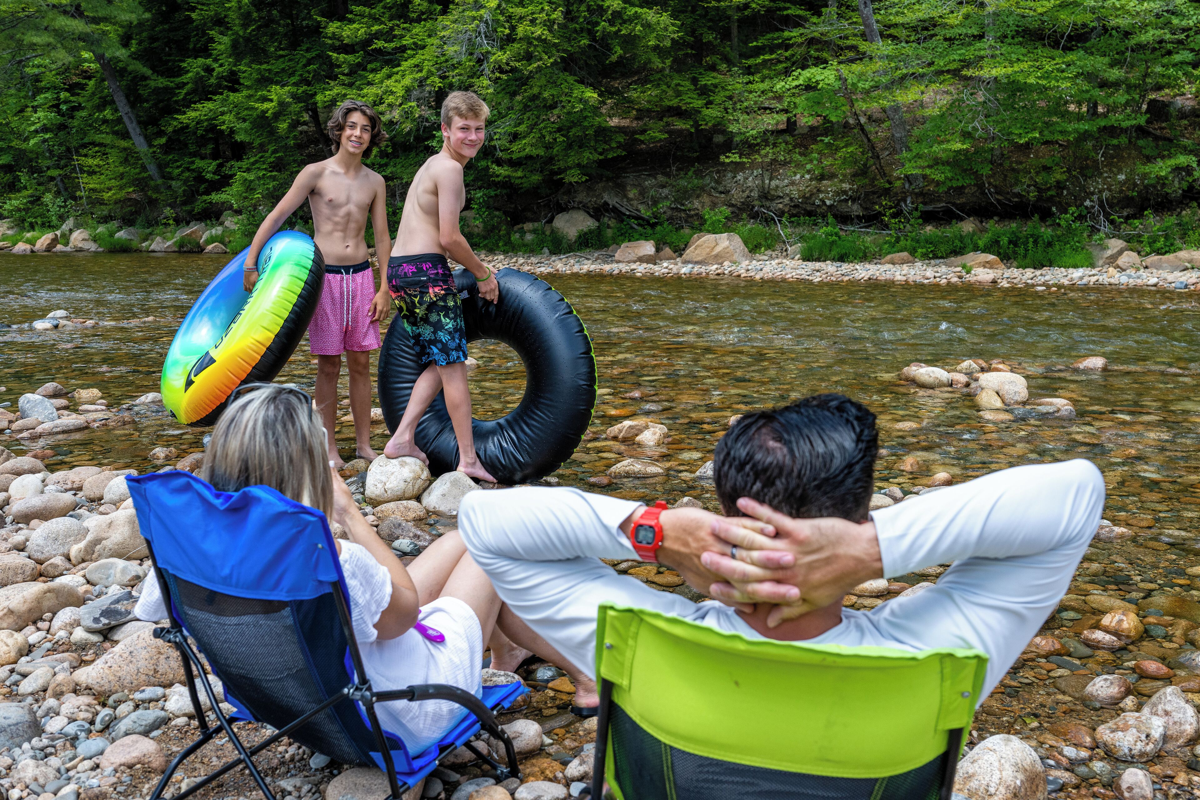 Un grupo de personas junto a un río, con rocas y vegetación al fondo.
