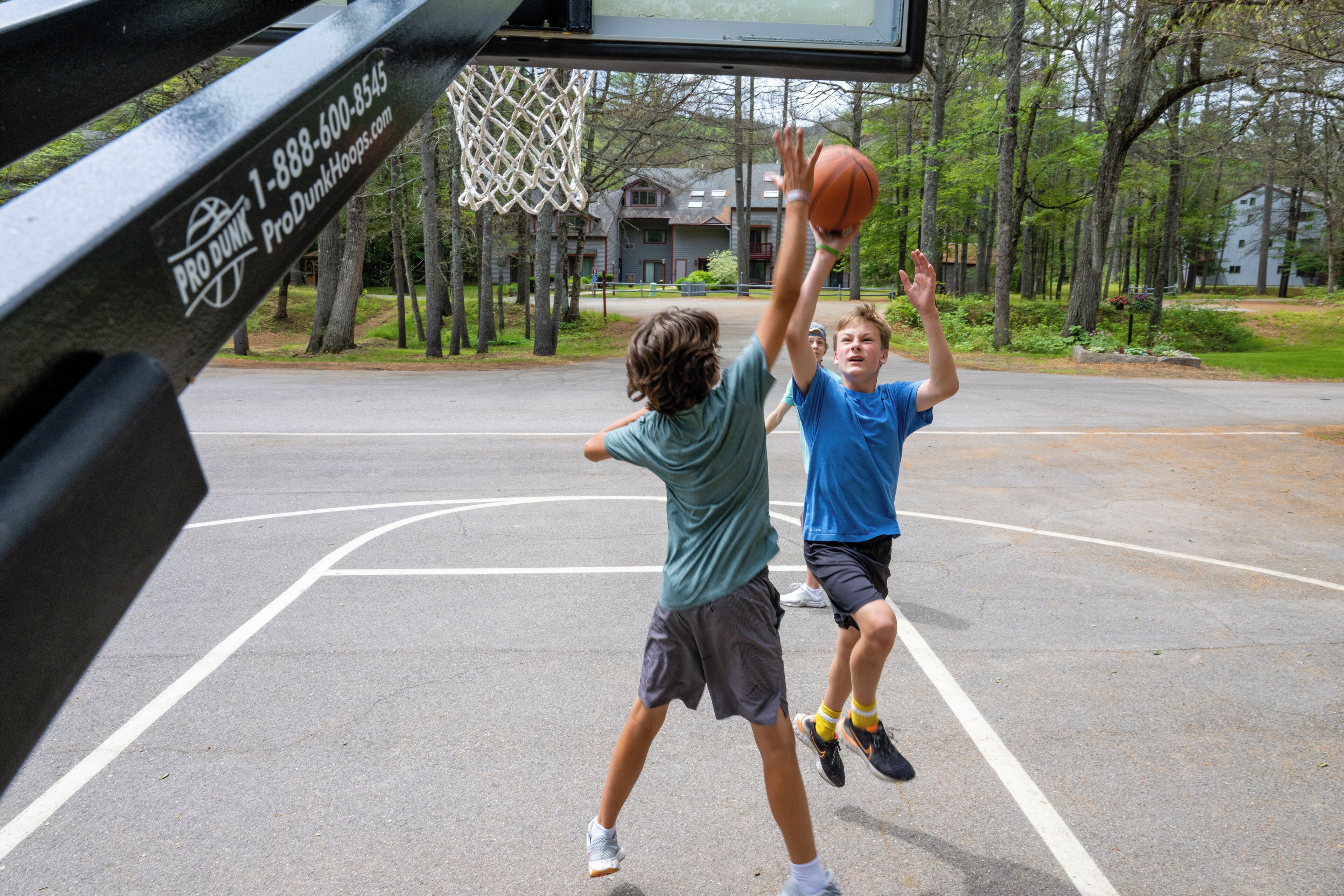 Two people playing basketball on an outdoor court with a basketball hoop.