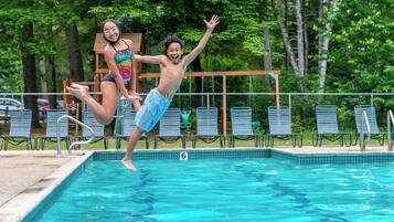 Una piscina con lettini e un molo di legno sullo sfondo.
