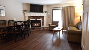 A living room with a fireplace, a dining area with chairs, a sofa, and a lamp. - Attitash Mountain Village (Bartlett)