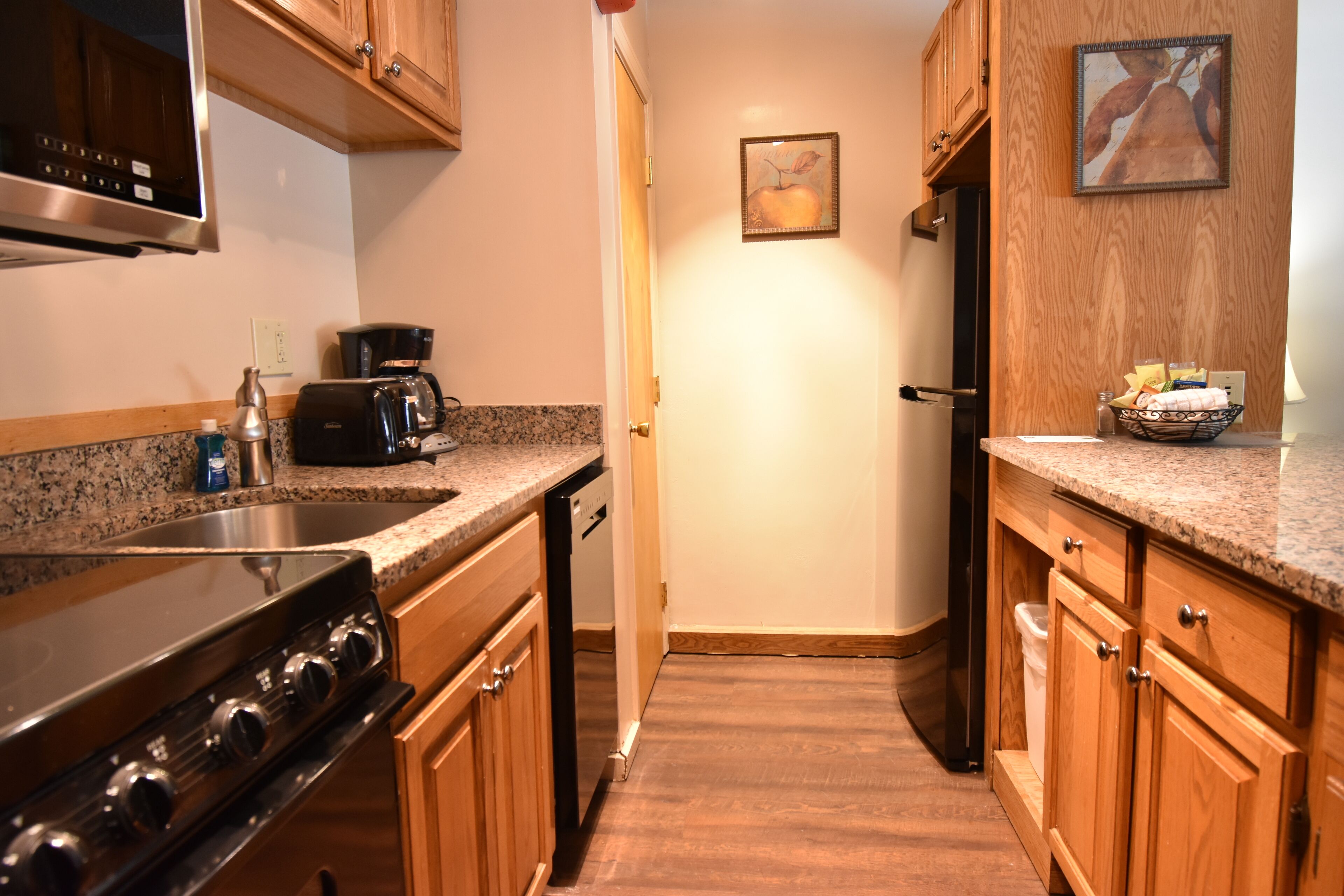 A kitchen with wooden cabinets, a stainless steel sink, a stove, a coffee maker, and a refrigerator.