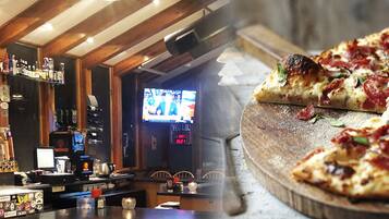 A bar area with a counter, shelves with bottles, and a television screen.
