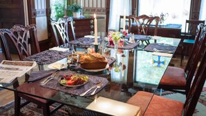 A dining area with a glass table, wooden chairs, and a variety of dishes and drinks. - Market Street Inn (Taylorville)