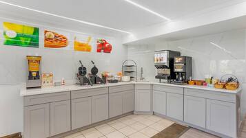 A modern kitchen with a waffle maker, coffee machine, and a sign for fresh coffee.