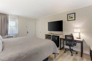 A hotel room with a large bed, a desk with a computer, a television, and a small desk lamp. - Quality inn Lancaster (Lancaster)