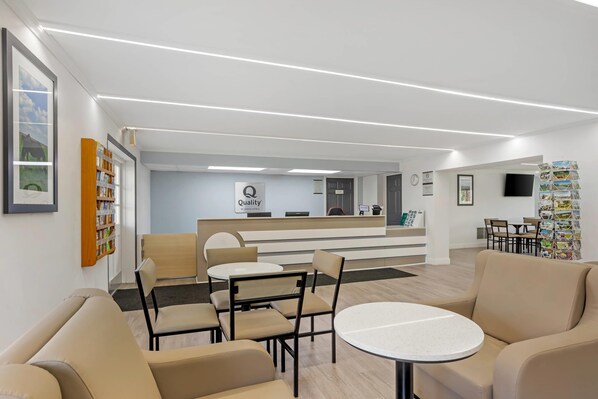 A hotel lobby with a reception desk, seating area, and a wall with framed pictures. - Quality inn Lancaster (Lancaster)