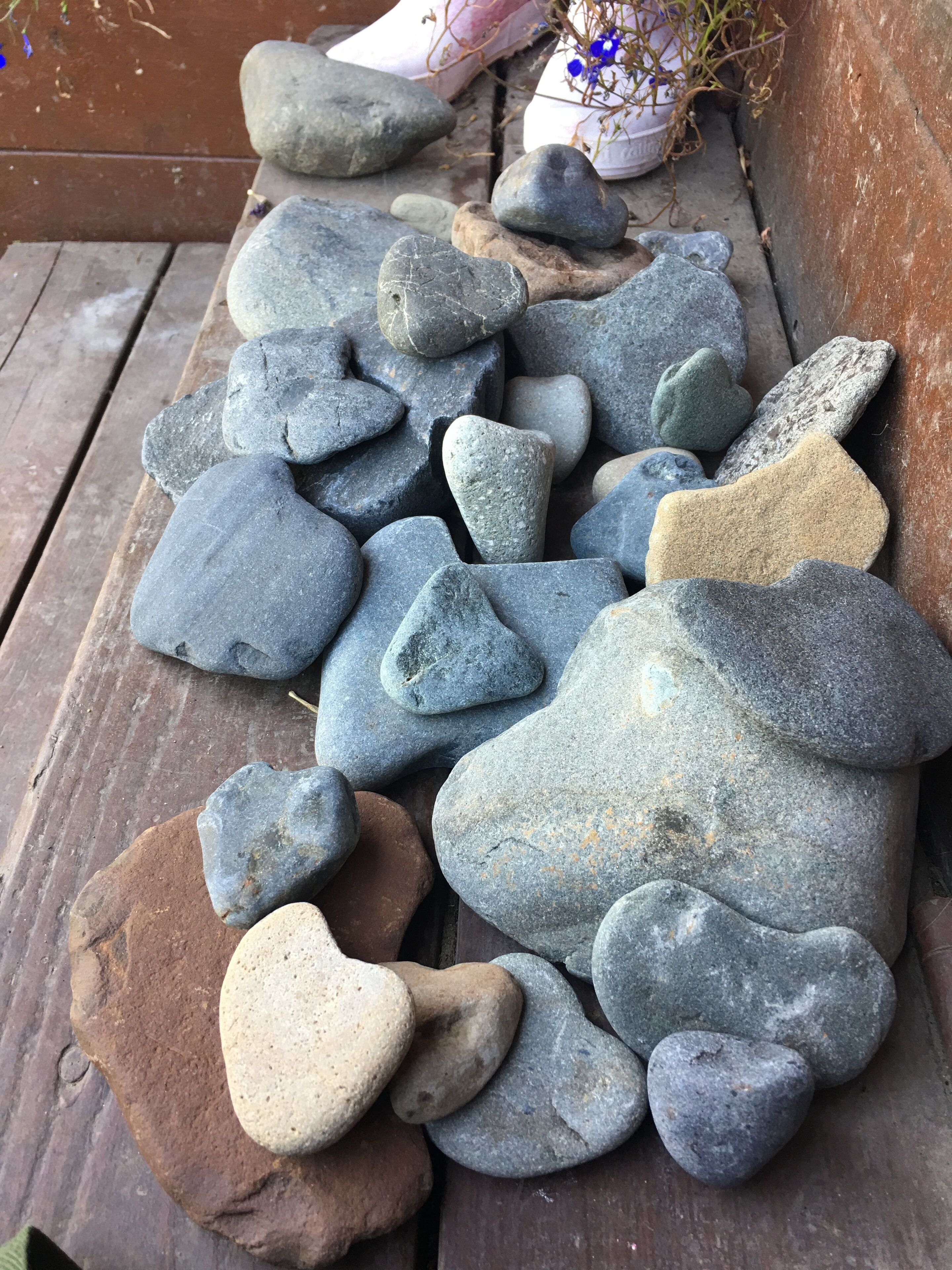 A wooden bench with a collection of smooth, rounded stones of various sizes and colors.