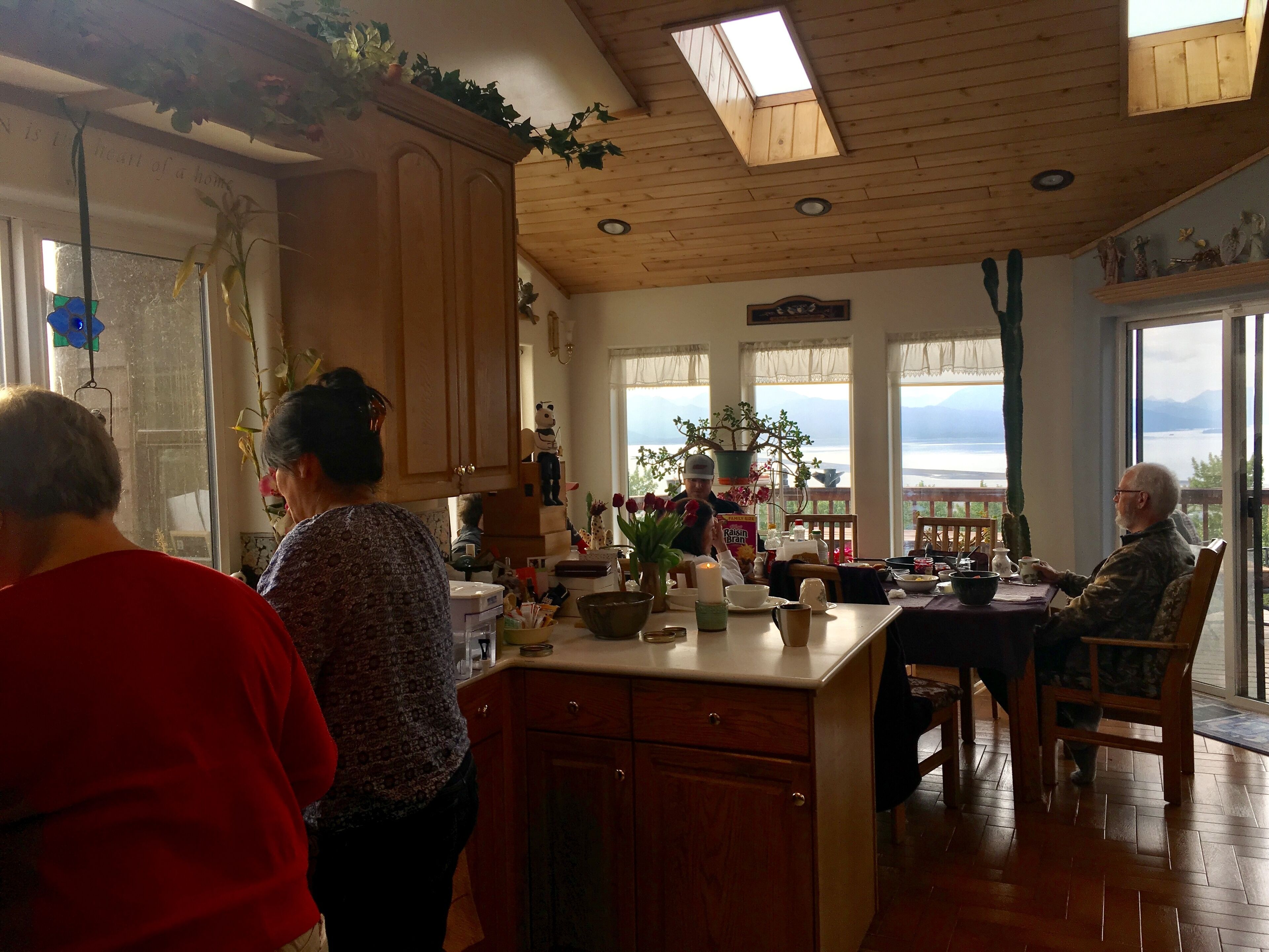 A cozy kitchen with wooden cabinets, a central island, and a dining area with a view of the mountains.