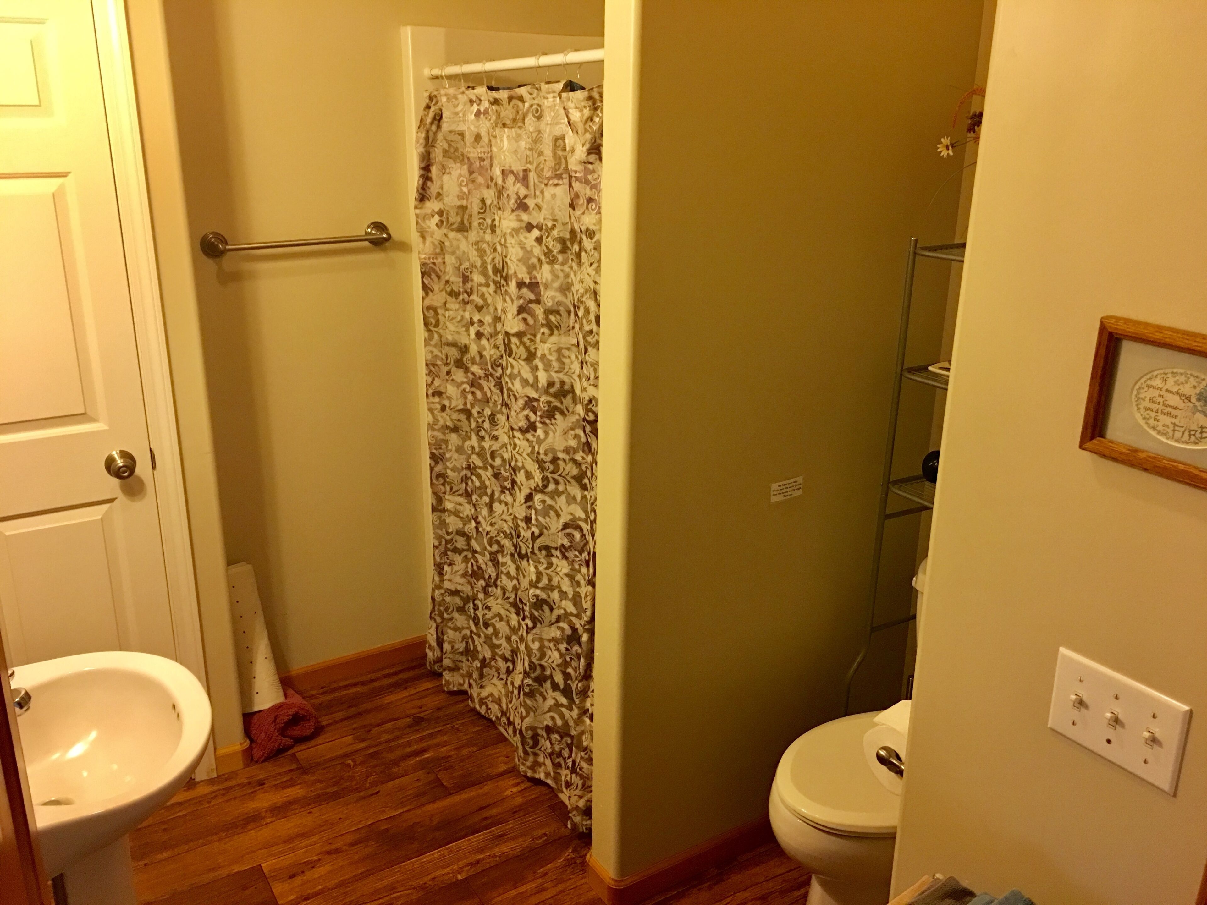 A bathroom with a shower curtain, a toilet, a sink, and a towel rack.