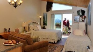 A bedroom with two beds, a sitting area with a table and chairs, and a view of the outdoors. - Majestic View B&B (Homer)