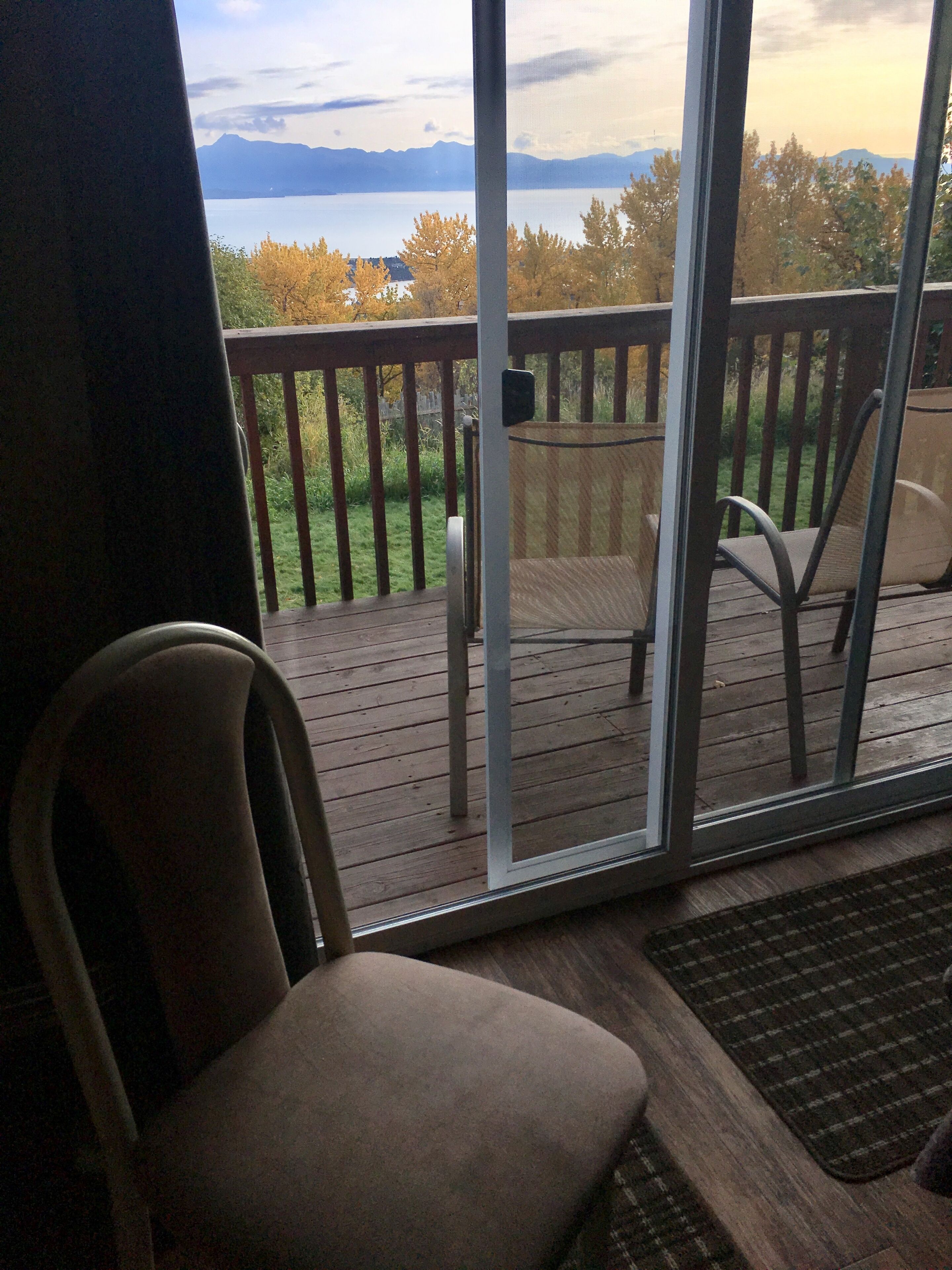 En terrasse med stol og bord, med udsigt over vand og bjerge.