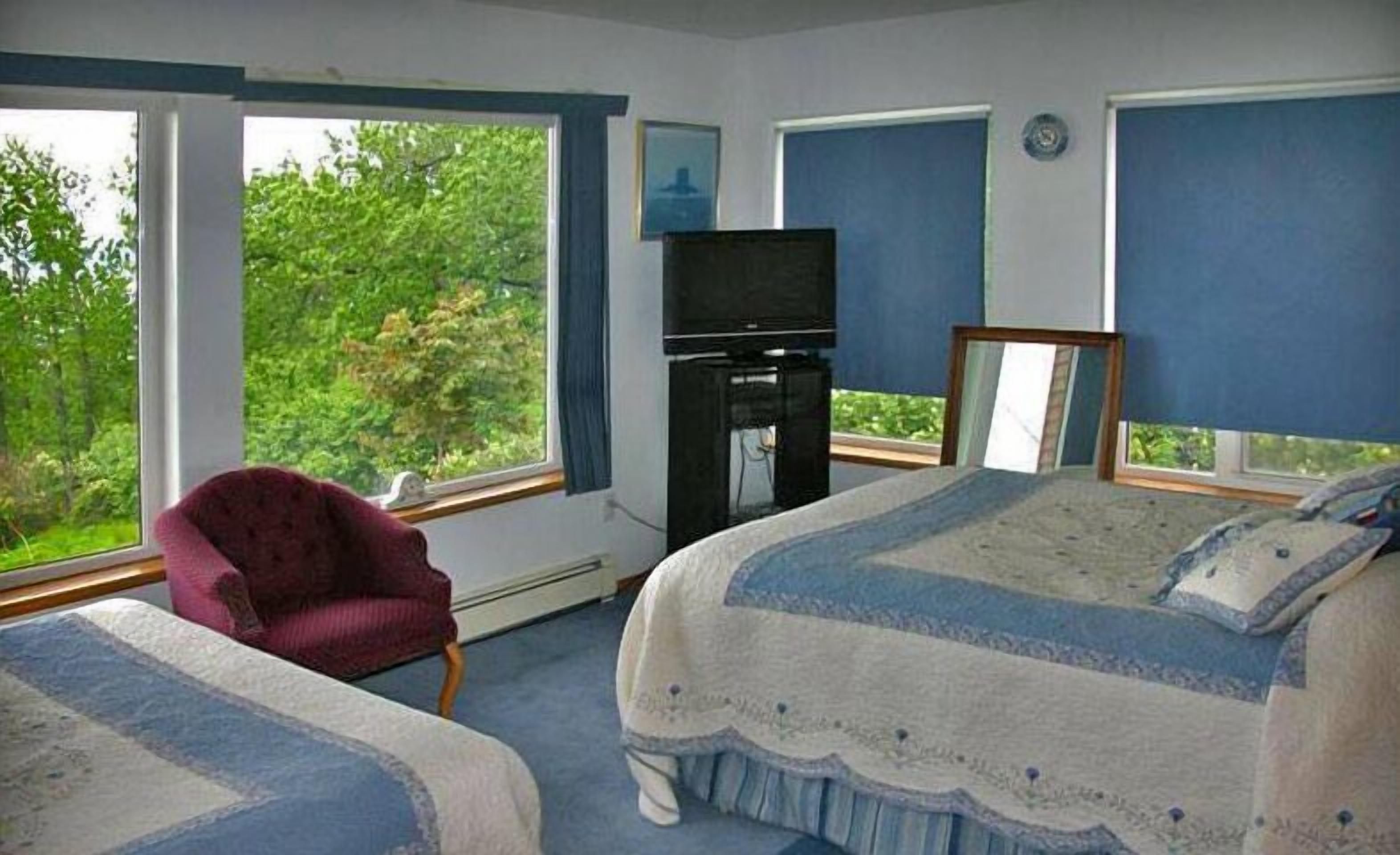 Une chambre avec deux lits, une télévision et une chaise.