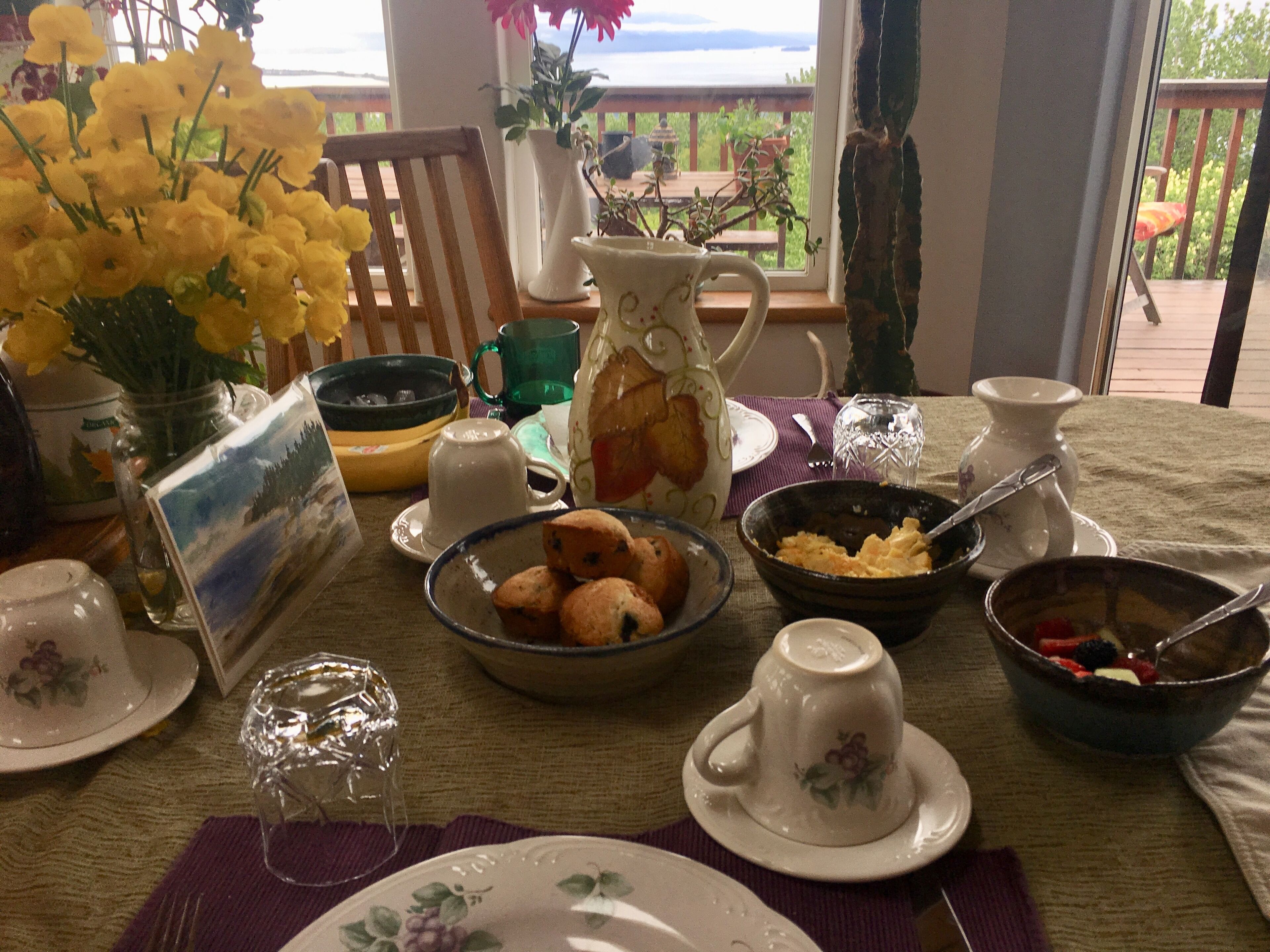A dining table set with various dishes, a pitcher, and a vase of yellow flowers.