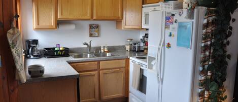 A kitchen with wooden cabinets, a white refrigerator, and a black countertop.