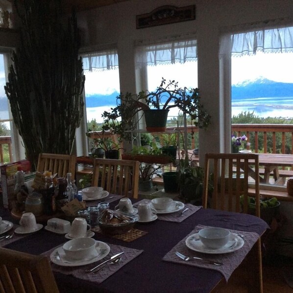 A dining area with a table set for four, overlooking a mountainous landscape.