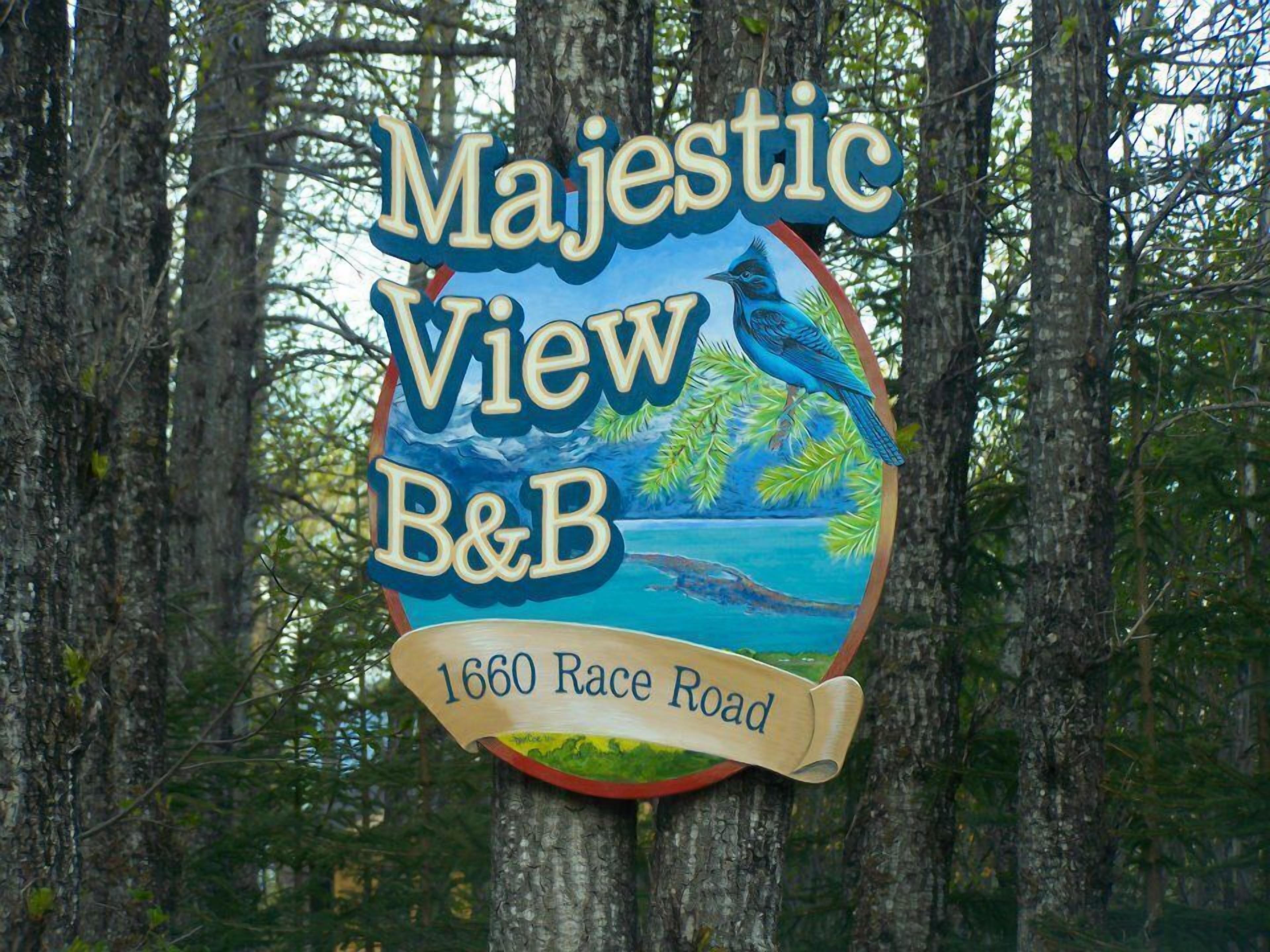 Une enseigne pour le B&B Majestic View, situé au 1660 Race Road, représentant un paysage tropical avec des oiseaux et de la végétation.