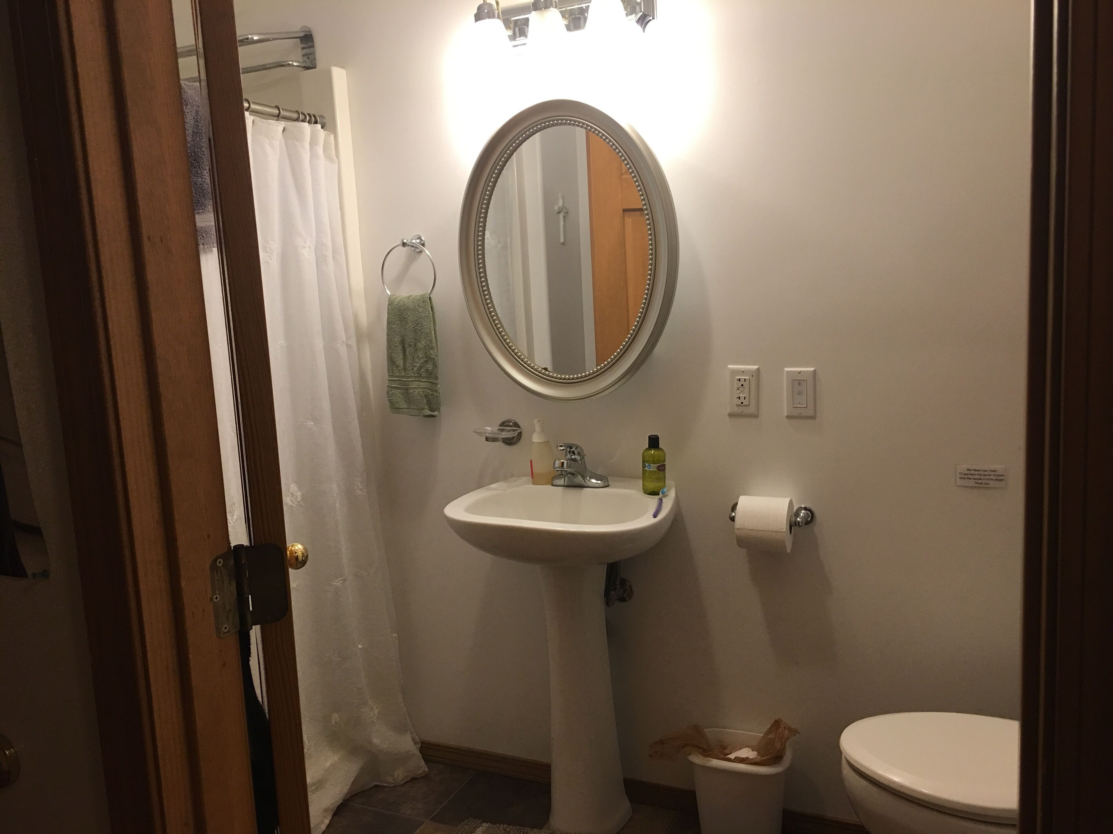 Un baño con lavamanos blanco, espejo, inodoro y cortina de ducha.