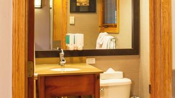 Une salle de bain avec un meuble-lavabo en bois, un évier, un miroir et des toilettes.