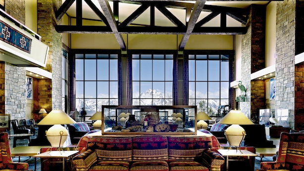 A spacious living room with a large window, a patterned sofa, and a fireplace.