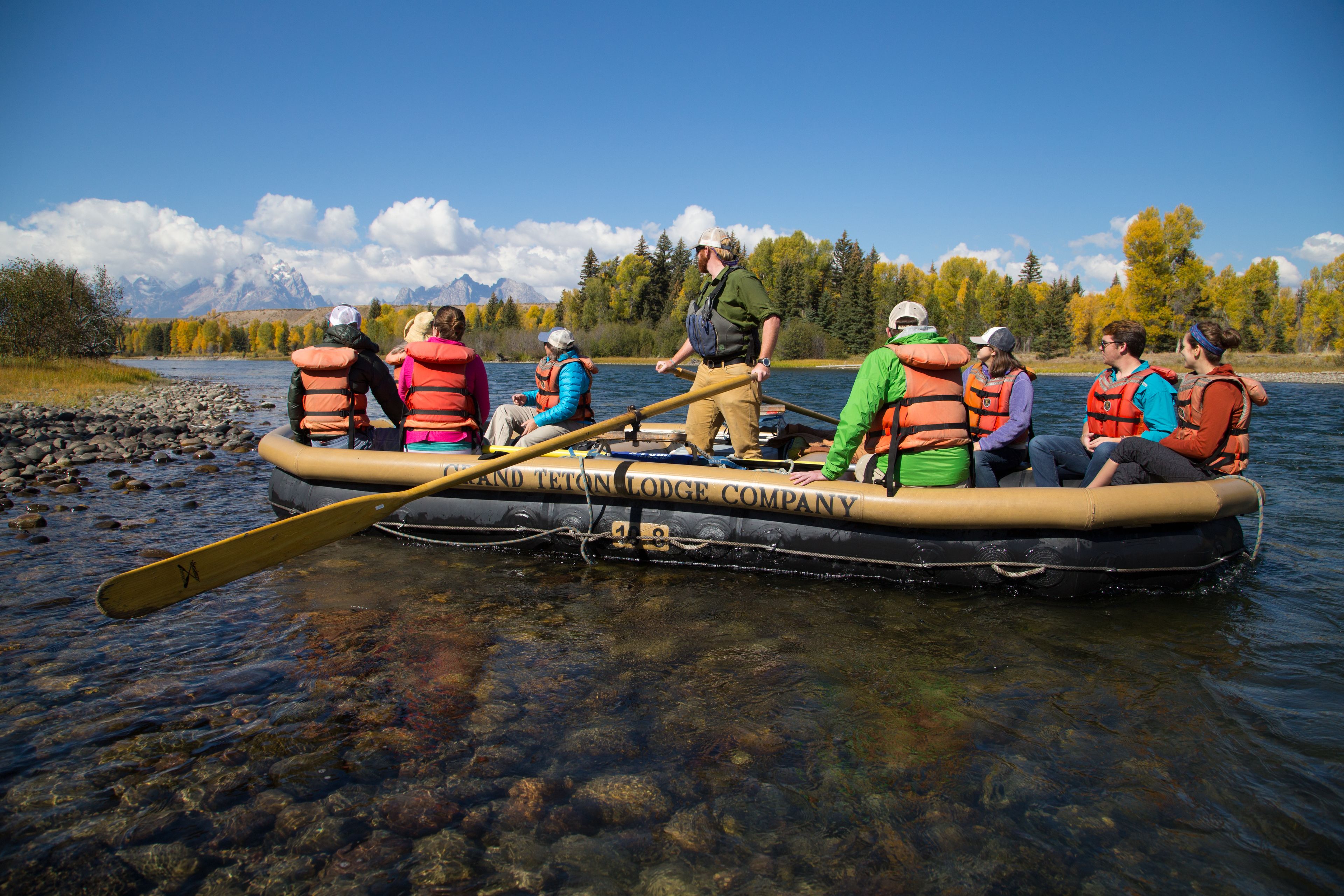 Een groep mensen in een raft op een rivier, met reddingsvesten.