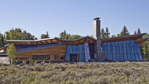 A modern building with a wooden facade, large windows, and a prominent chimney.