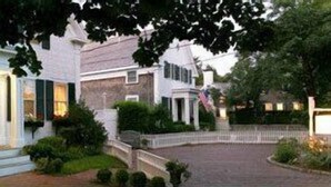A traditional two-story house with a front porch, a flag, and a well-maintained garden. - The Ashley Inn (Edgartown)