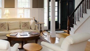 A living room with a beige sofa, two armchairs, a coffee table, and a fireplace. - The Ashley Inn (Edgartown)