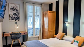 A hotel room with a bed, a desk, a chair, a wardrobe, and a window with blinds. - H33 hôtel (Nice)