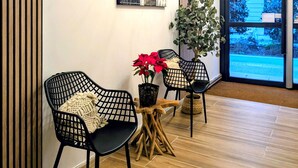 A modern interior with black mesh chairs, a wooden table, a potted plant, and a unique ceiling light fixture. - H33 hôtel (Nice)