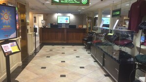 Un vestíbulo de hotel con un mostrador de recepción, un indicador para el ascensor al piso del casino y una exhibición de recuerdos.