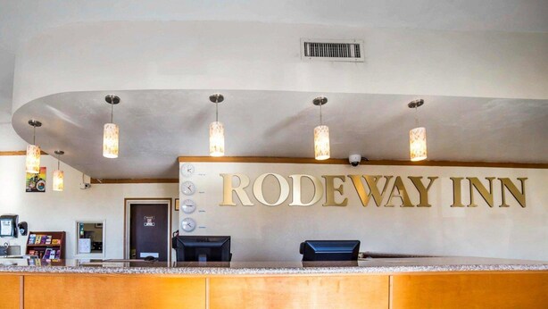 L’espace d’accueil du Rodeway Inn est doté d’un comptoir en bois, d’une horloge et d’une caméra de surveillance placée au-dessus de l’entrée.