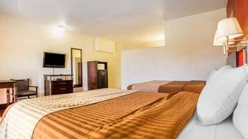 Una habitación de hotel con una cama, un escritorio con una silla, un televisor y un armario.