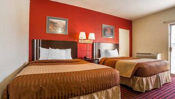 Habitación de hotel con dos camas, una pared decorada en rojo y una alfombra a cuadros rojo y negro.