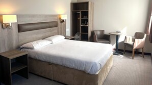A hotel room with a bed, bedside tables, a wardrobe, a desk, and two chairs. - The Priory Hotel (Beauly)