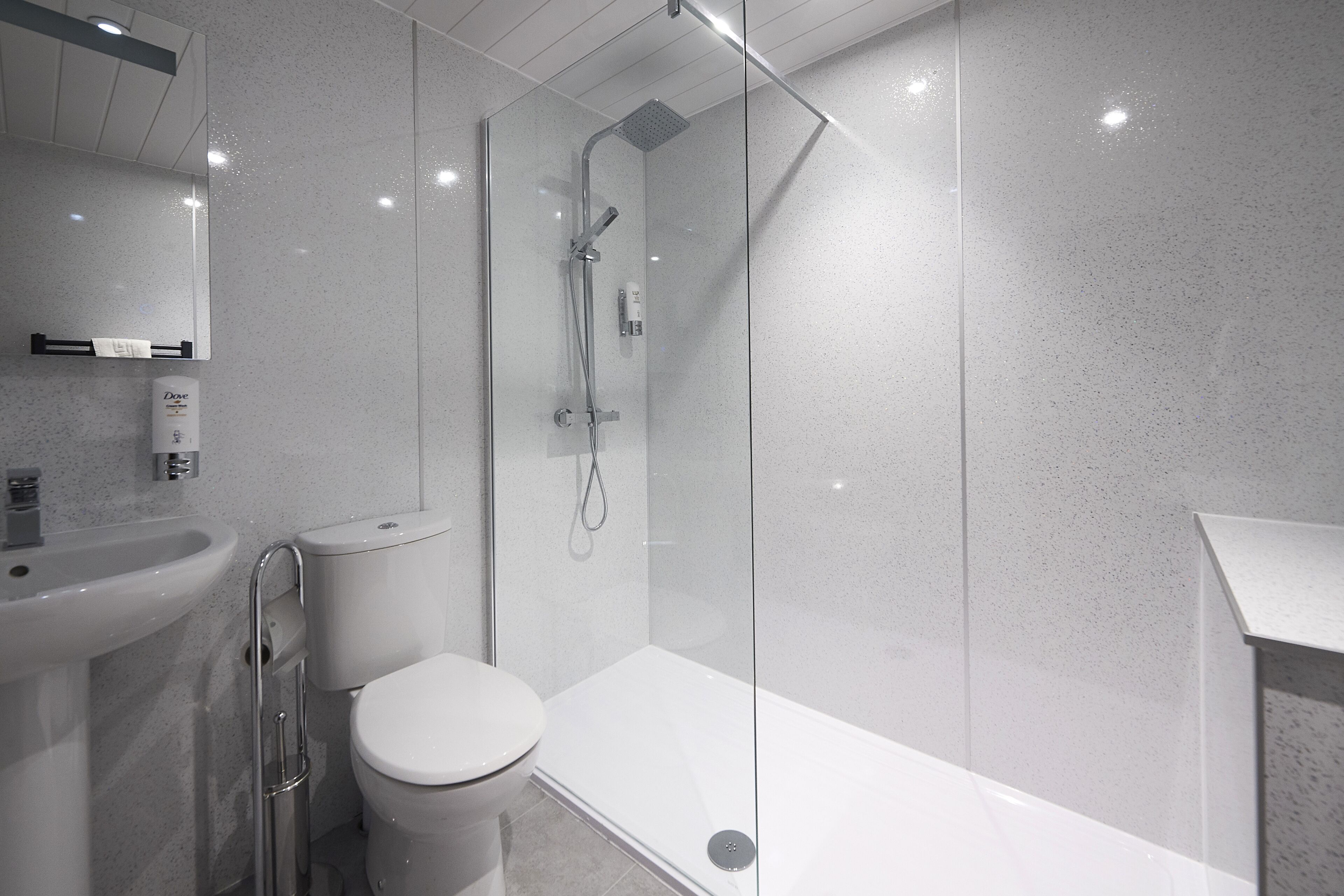 A modern bathroom with a glass-enclosed shower, a white toilet, and a sink.
